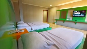 A hotel room with two beds, a small table with a phone, a green-framed TV, and a green-framed shelf with toiletries. - Kita Hotel (Tanjung Pinang)
