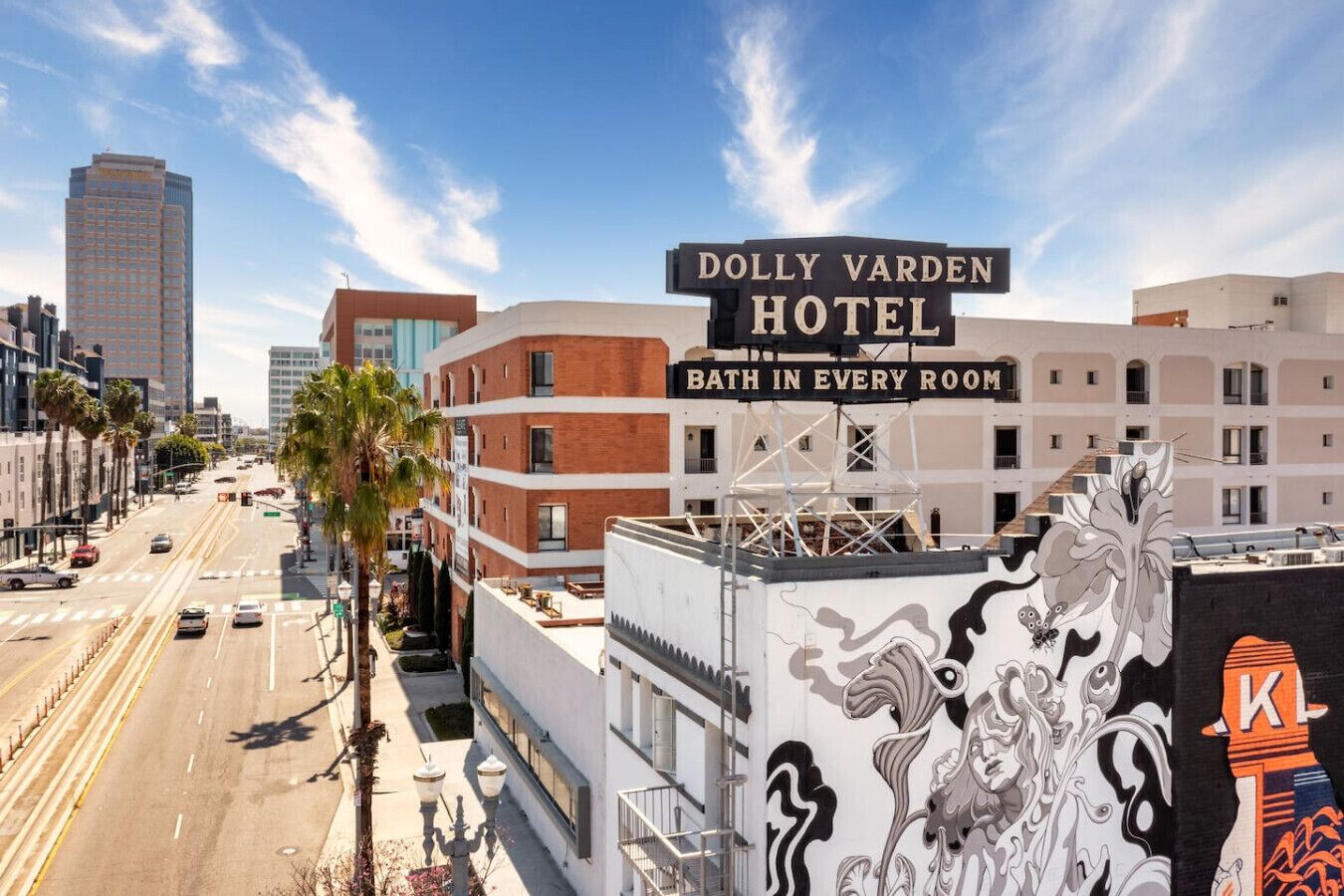 Hotel Dolly Varden con un cartel que dice 'Baño en cada habitación' y vistas de la calle y edificios circundantes.