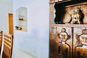 A room with a wooden cabinet, a small shelf with decorative items, and a wooden chair.