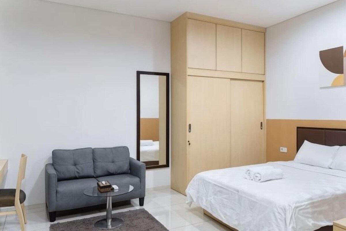 A modern hotel room with a bed, a sofa, a small table, and a wardrobe.