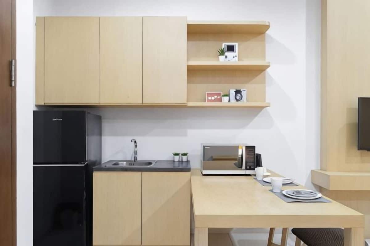 Une cuisine compacte équipée d’un réfrigérateur, d’un évier, d’un four à micro-ondes et d’une petite table à manger.
