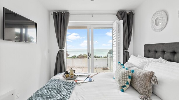 A bedroom with a bed, a TV, a view of the sea, and a balcony. - Osprey 3, The Cove - Sea view - On site pool (Brixham)