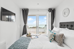 Une chambre avec un lit, une télévision, une vue sur la mer et un balcon.