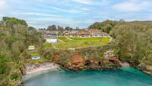 A coastal property with a large building complex, a rocky shoreline, and a clear view of the sea. - Osprey 3, The Cove - Sea view - On site pool (Brixham)