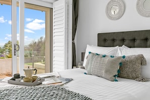 Relax in a serene bedroom with a large bed and sliding door to an outdoor area offering a view of lush greenery.