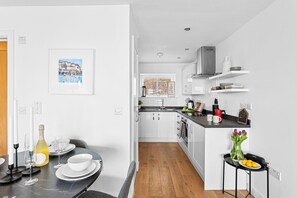 Enjoy meals in the kitchen with an oven and stainless steel range hood, adjacent to a dining area with a table for two.