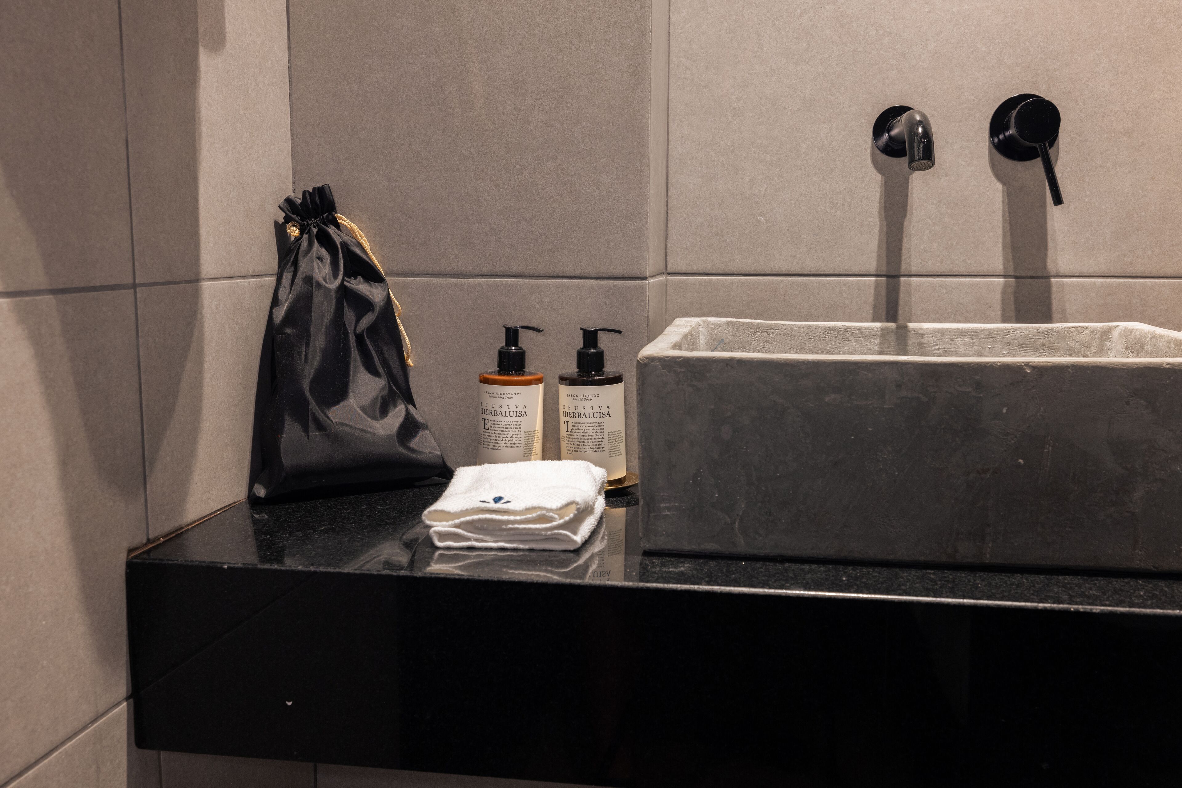 A bathroom with a black countertop, a white towel, and two bottles of lotion.