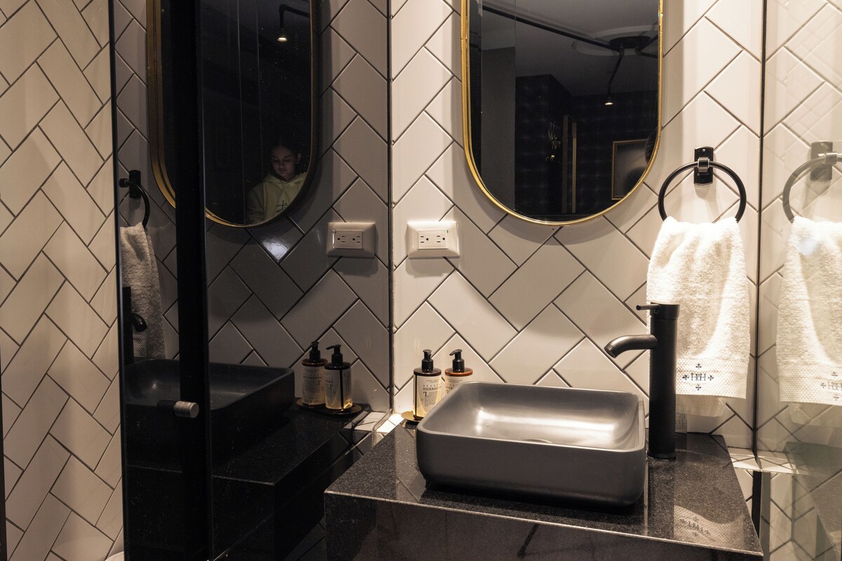 A bathroom with a black sink, two mirrors, and a towel rack.