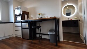 A compact kitchen with a wooden countertop, a built-in oven, and a small refrigerator. There is a stool and a trash bin near the counter. - Penelope garden ,5 min to Botany shopping mall (Auckland)