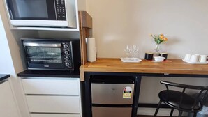 A compact kitchenette with a microwave, refrigerator, and a wooden table with a chair. - Penelope garden ,5 min to Botany shopping mall (Auckland)