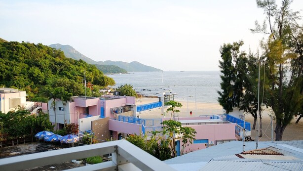 A coastal view with a beach, buildings, and a mountainous backdrop.