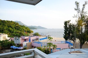 A coastal view with a beach, buildings, and a mountainous backdrop. - Bayshore Inn (Lamma Island)