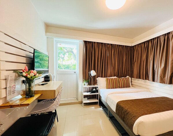 A hotel room with a bed, a desk with a computer, a TV, and a window with curtains. - Bayshore Inn (Lamma Island)