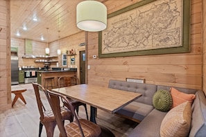 Un interno in legno con un'area pranzo, una mappa appesa al muro e una cucina sullo sfondo.