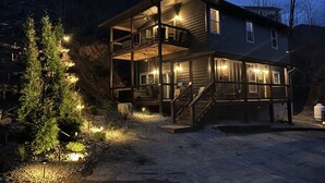 Eine zweistöckige Holzhütte mit Balkon, Treppe und gut beleuchteter Fassade.