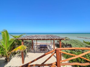 Abrigo de praia de madeira com telhado de palha, com vista para a praia.
