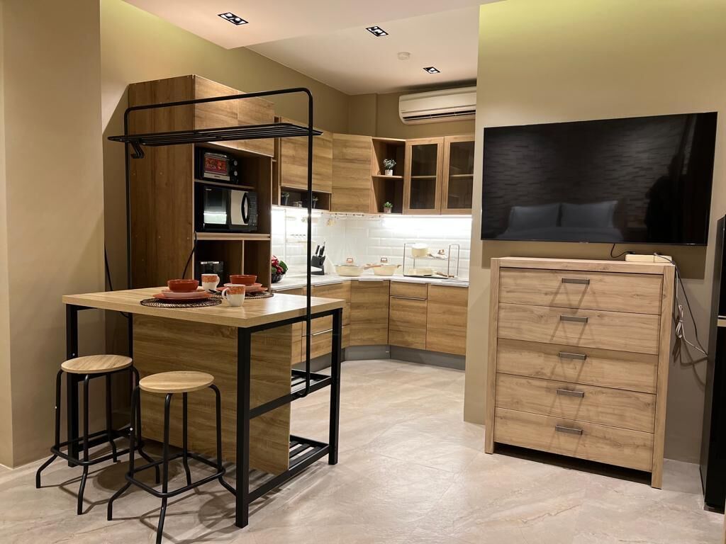 A modern kitchen with a wooden island, stools, and a built-in microwave.