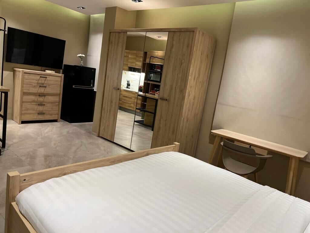 A bedroom with a bed, a desk, a wardrobe, and a mirrored closet door.