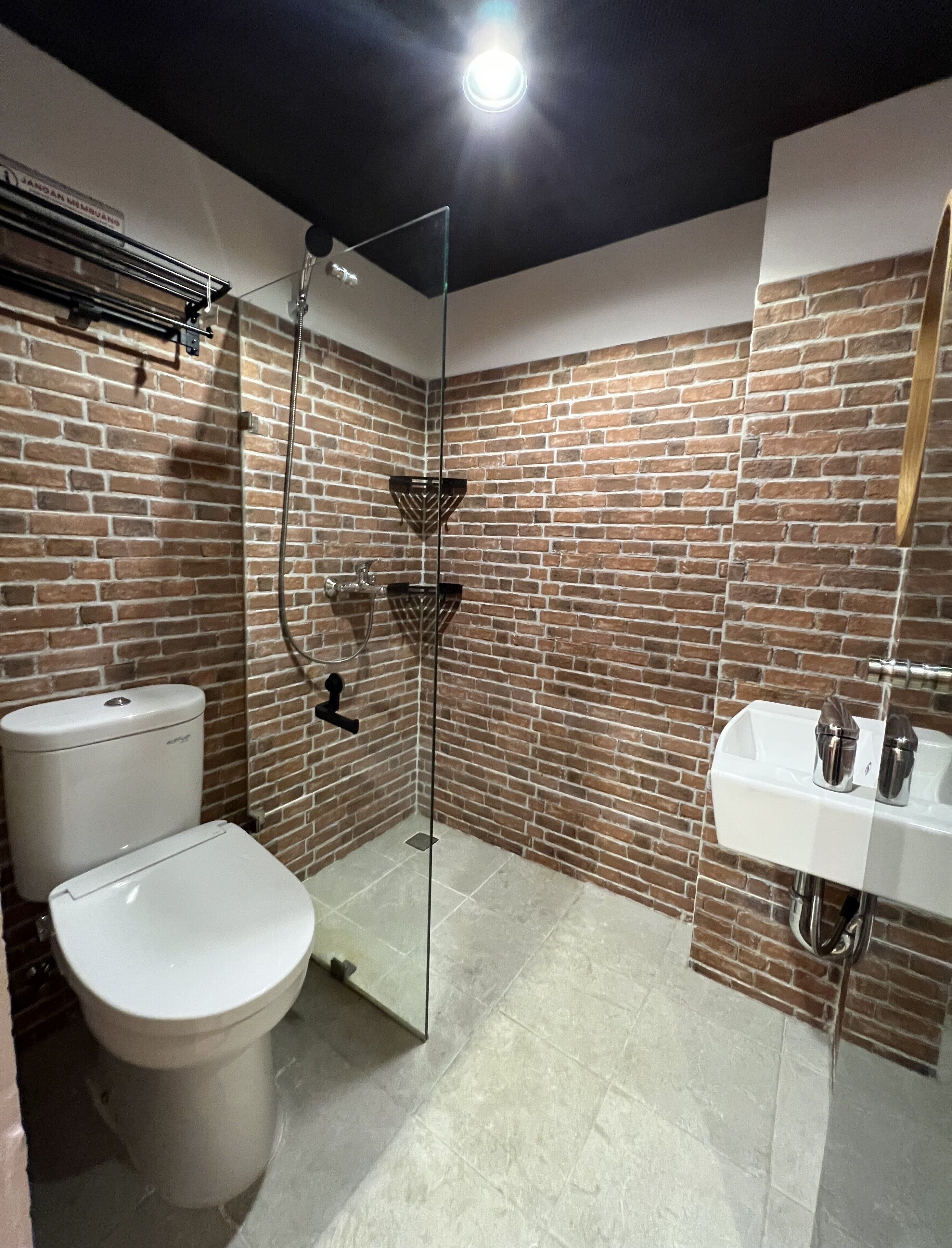 A bathroom with a glass shower enclosure, a toilet, and a sink with a mirror.