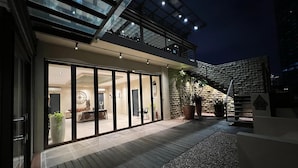 A modern building with a glass facade, a wooden deck, and a stone wall.