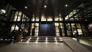 A building entrance with a large door, steps leading up to it, and a potted plant on the left.