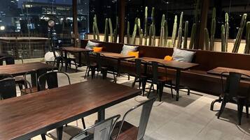 An outdoor dining area with wooden tables and benches, surrounded by tall cacti.