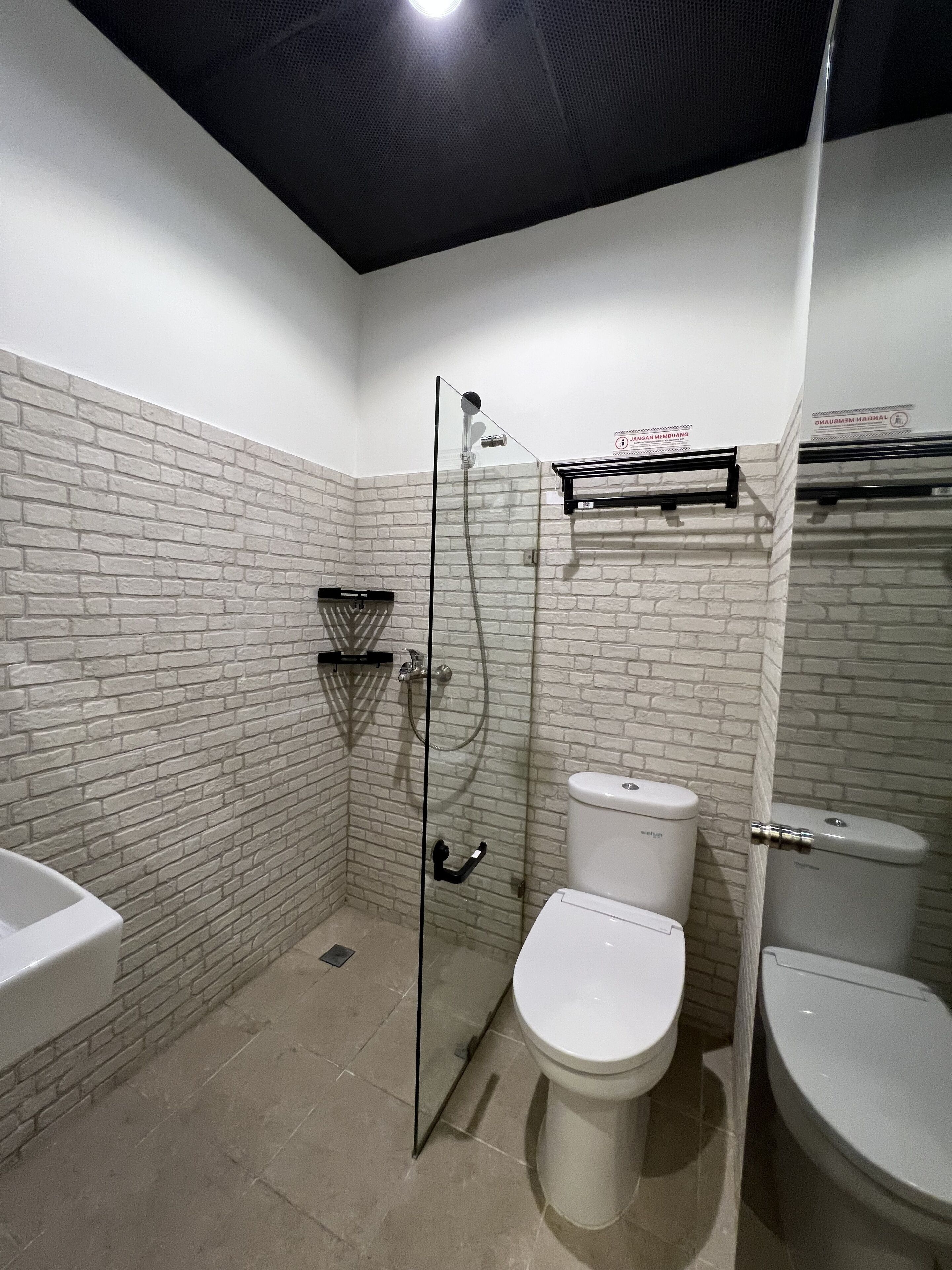 A bathroom with a glass-enclosed shower, two toilets, and a sink.