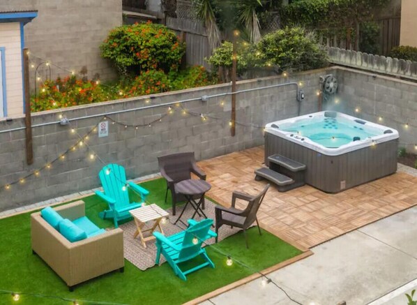 A backyard with a hot tub, outdoor furniture, and string lights. - 1 block from beach, hot tub, 3bd/3ba near SF and SFO airport (Pacifica)