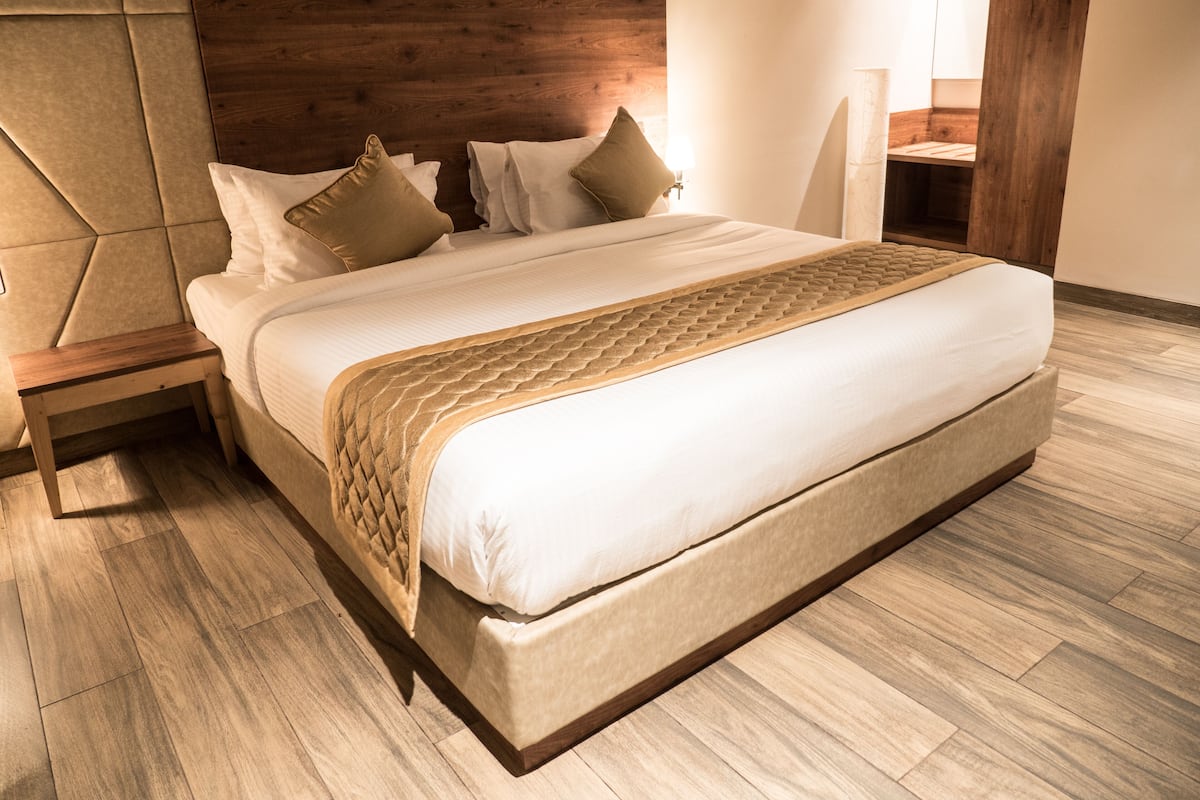 Une chambre moderne avec un grand lit, une tête de lit en bois et une table de chevet.