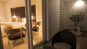 Une chambre d’hôtel moderne avec un lit, deux chaises, une petite table et une plante en pot.