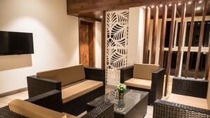 Un espace extérieur moderne, aménagé avec des meubles en osier et une table en verre.