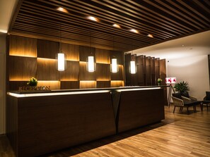 A reception desk with a wooden finish, overhead lighting, and a sign that reads "RECEPTION".