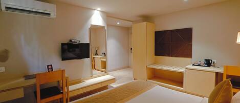 A hotel room with a bed, a desk, a chair, a television, and a mirror.