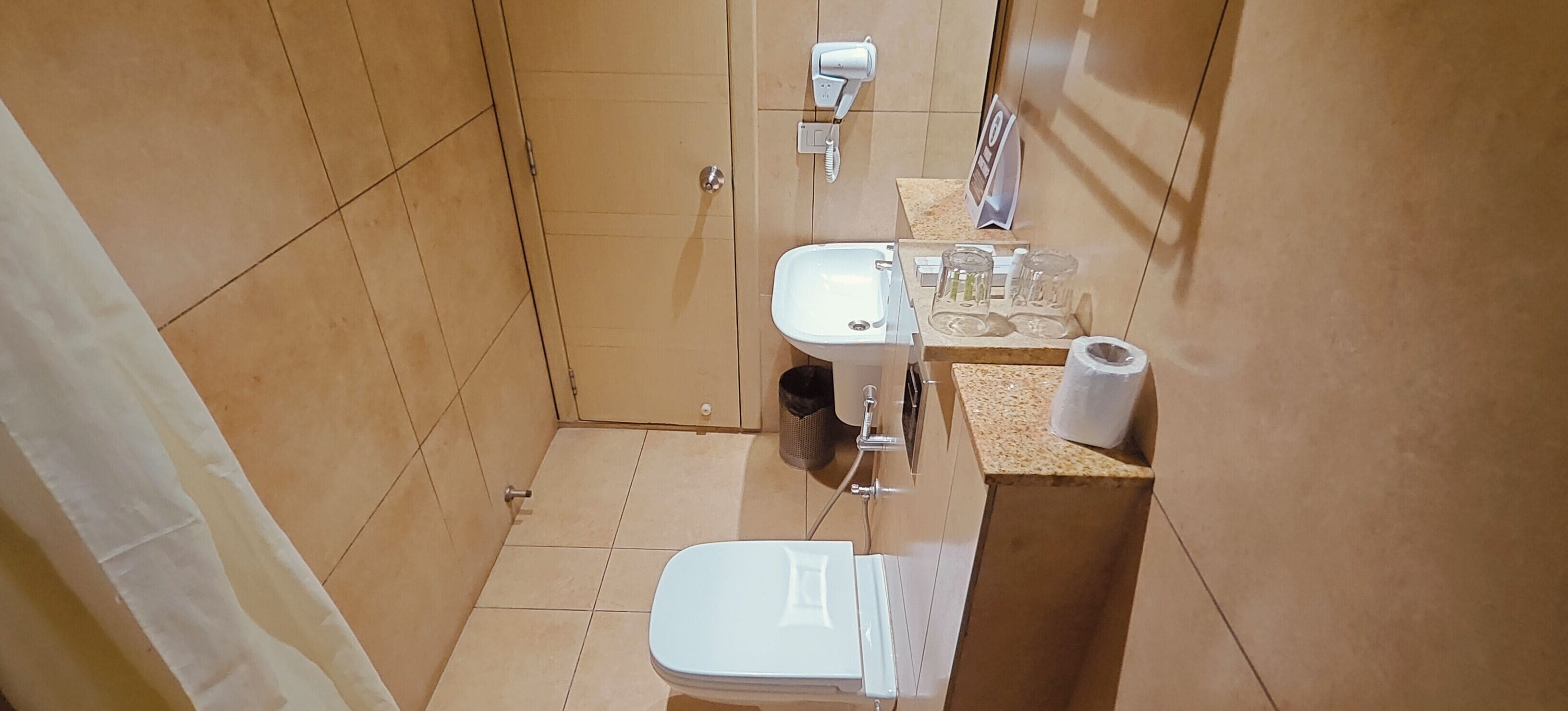 A small bathroom with a toilet, sink, and a towel dispenser.