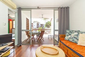 A room with a TV, a sofa, a dining table with chairs, and a balcony with a table and chairs. - Exotica - In the heart of Saint-Gilles-les Bains (Saint Paul)