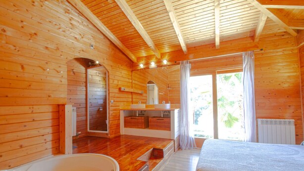 A wooden cabin with a bathroom featuring a bathtub, a sink, and a mirror. - Club Villamar - Rent your dream villa and spend an unforgettable holiday (Calonge)