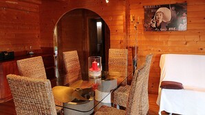 A wooden interior with a glass table surrounded by wicker chairs, a white sofa, and a poster on the wall. - Club Villamar - Rent your dream villa and spend an unforgettable holiday (Calonge)