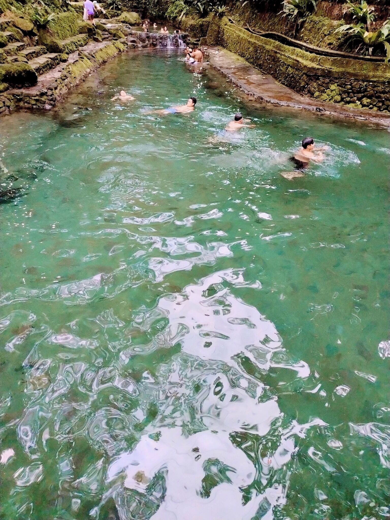 Una fuente termal natural con aguas claras y alrededores rocosos.