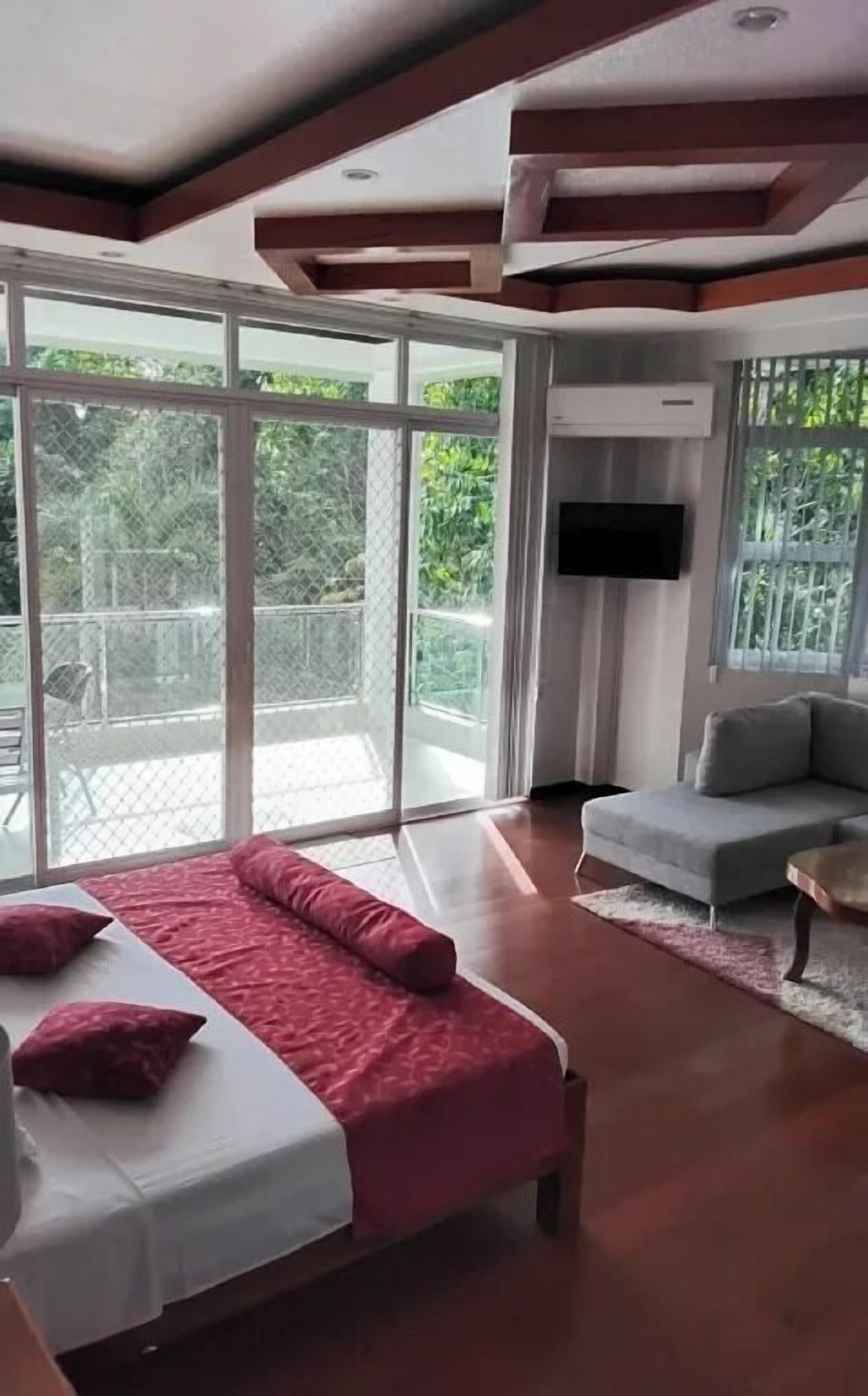 A modern bedroom with a large bed, a sofa, and a TV.