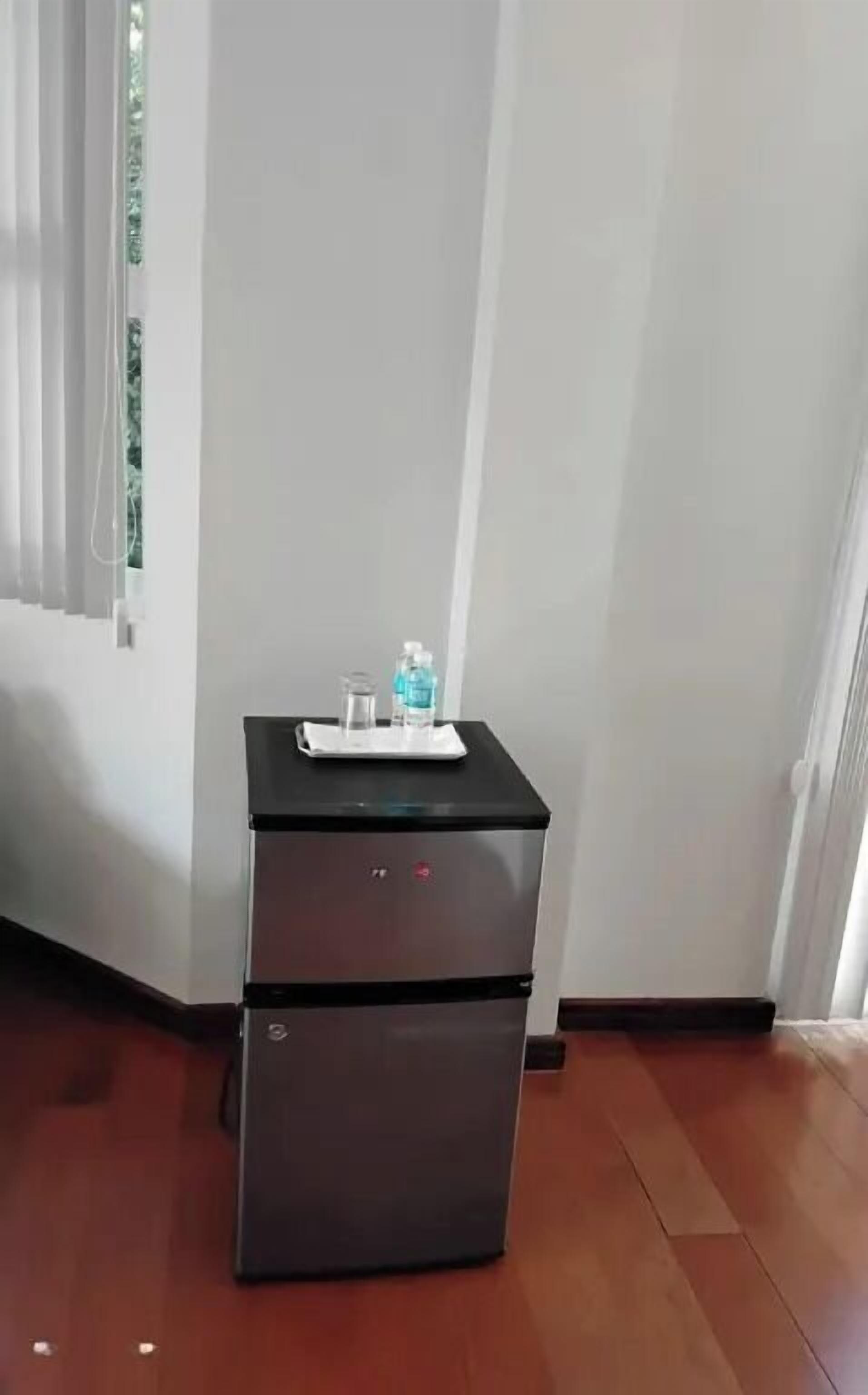 A compact kitchenette with a refrigerator, a small countertop, and a water bottle.