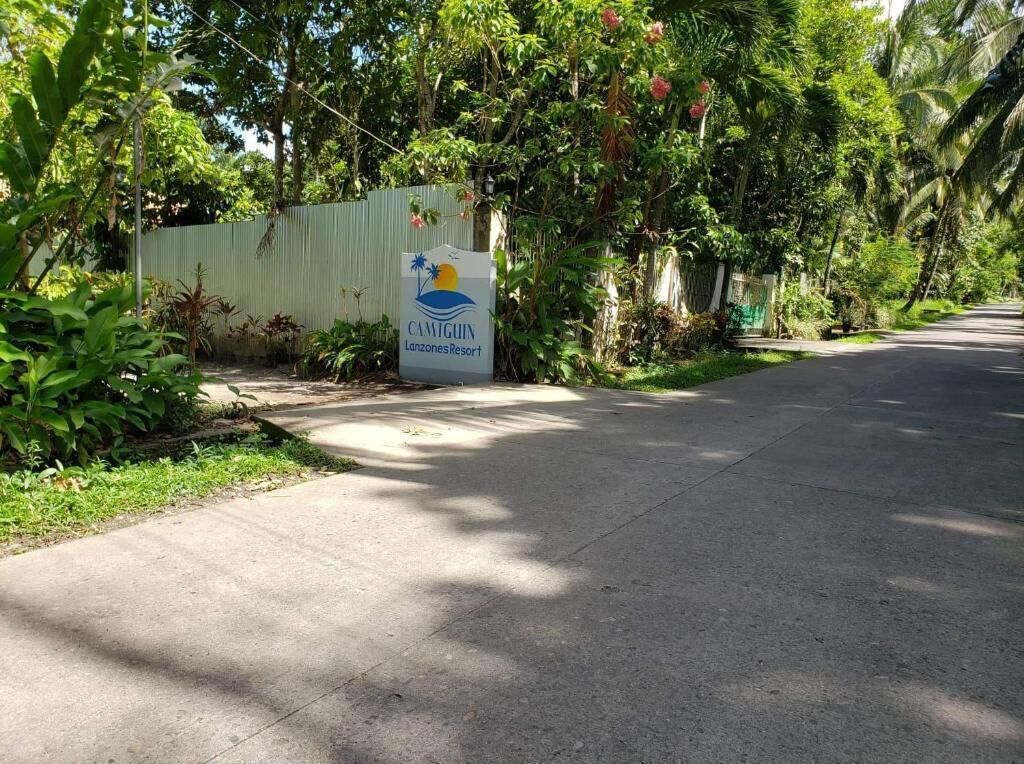 Señal para el Camiguin Lanzones Resort con un jardín tropical de fondo.
