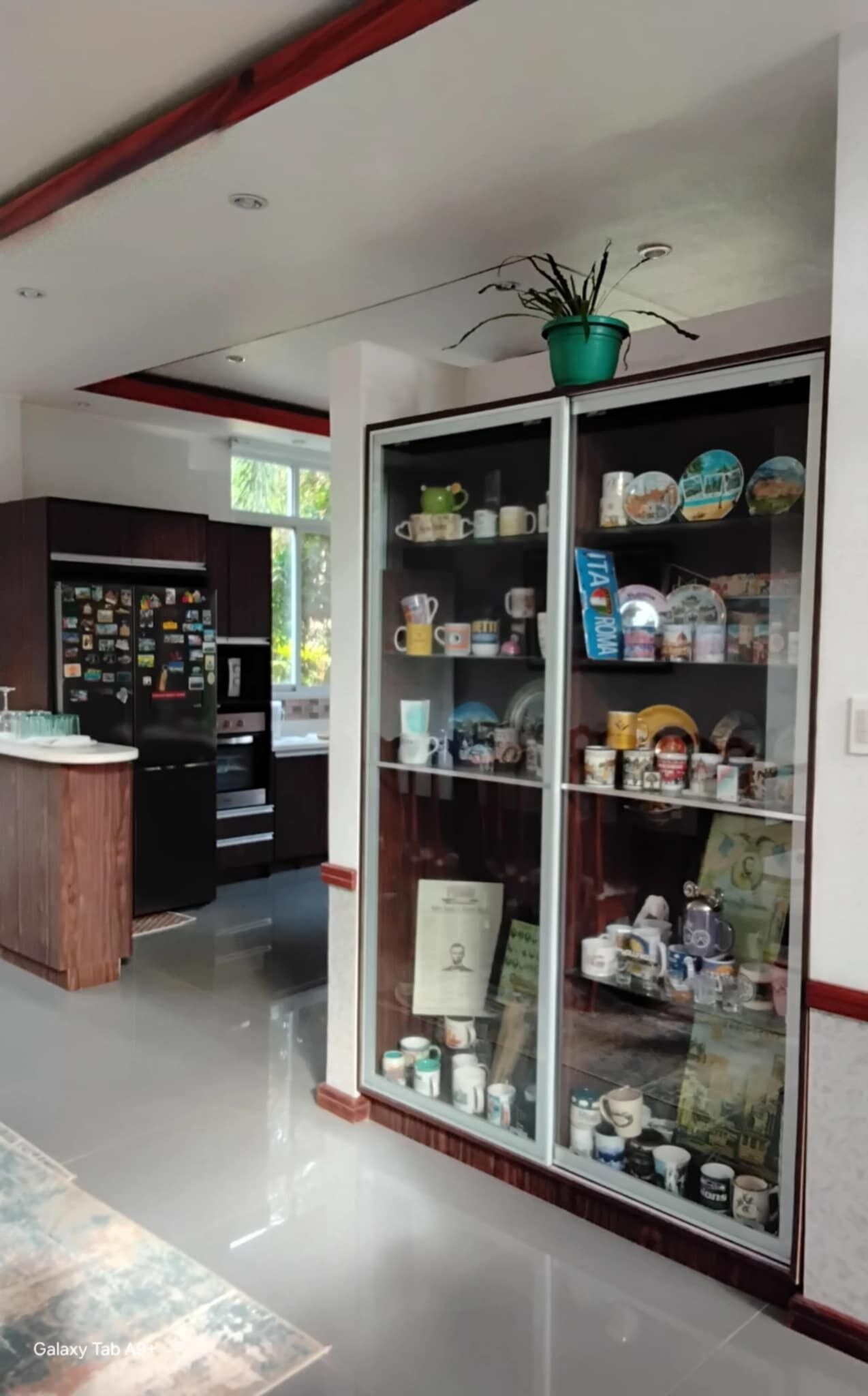 Una cocina moderna con refrigerador empotrado, encimera de madera y vitrina de vidrio con utensilios de cocina.