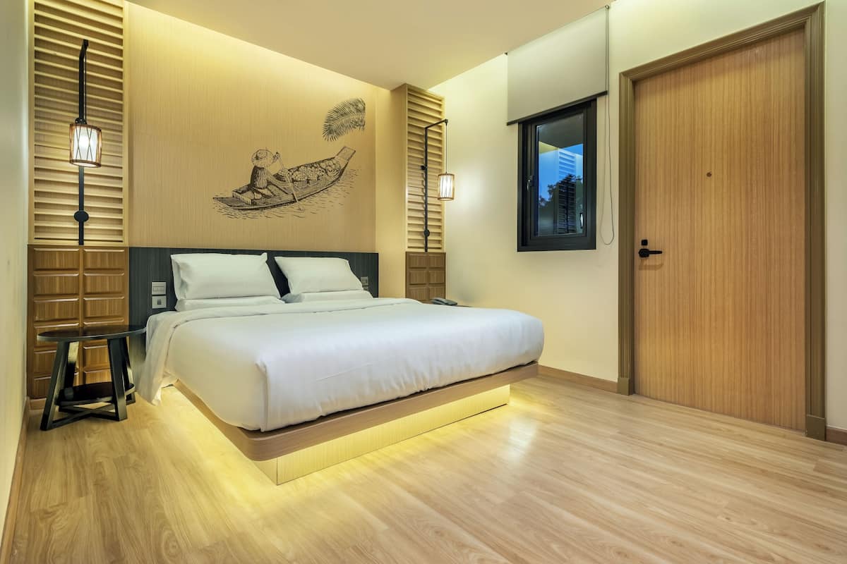 Une chambre moderne avec un lit, un plancher en bois, des œuvres d’art murales et une fenêtre.
