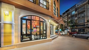 Un hotel con un amplio ventanal de arco, un restaurante a la vista y un estacionamiento con coches.