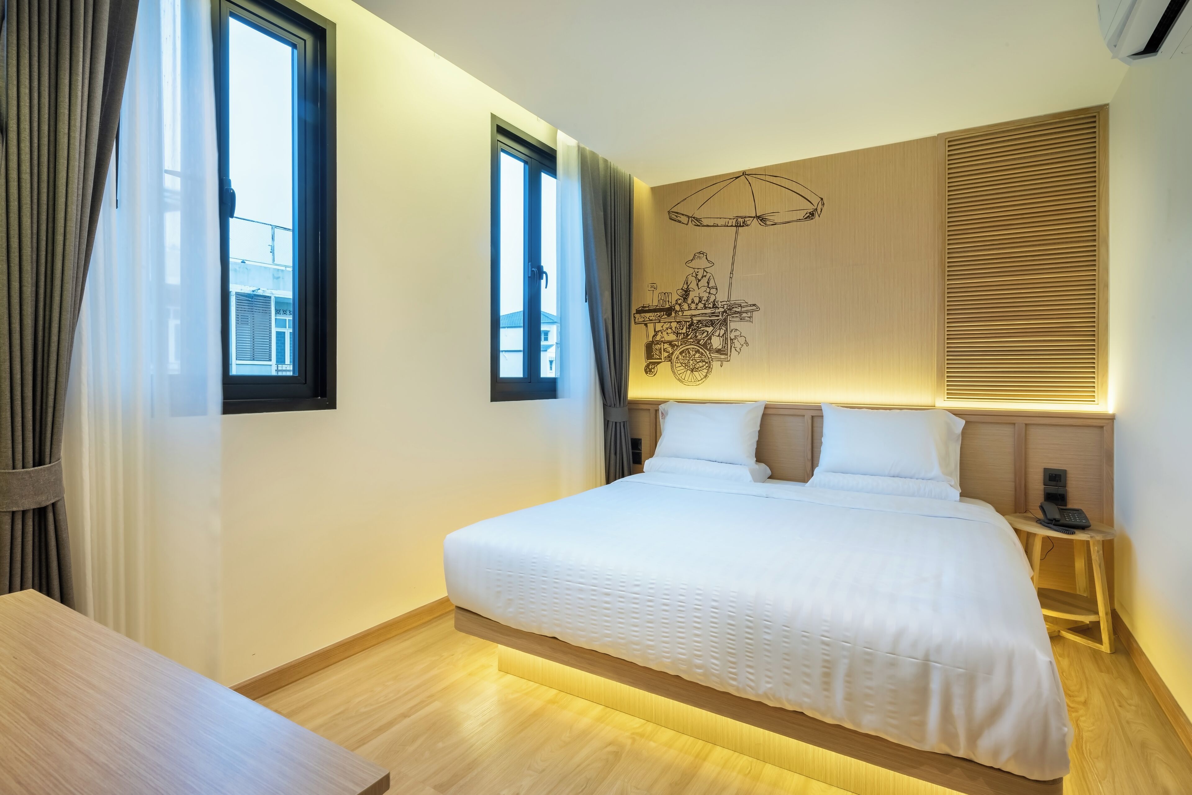 A modern hotel room with a large bed, bedside tables, and a wall-mounted artwork.