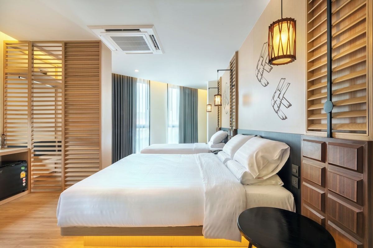 Une chambre d’hôtel moderne avec un grand lit, des panneaux de bois et un bureau équipé d’un ordinateur.