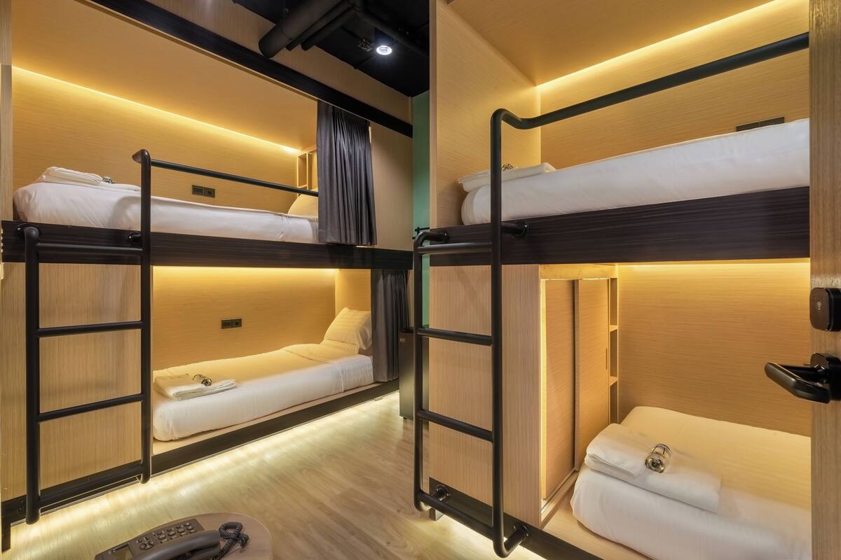 Une chambre avec un lit superposé, des murs en bois et un plancher en bois. On y trouve une petite table sur laquelle est posée une télécommande.