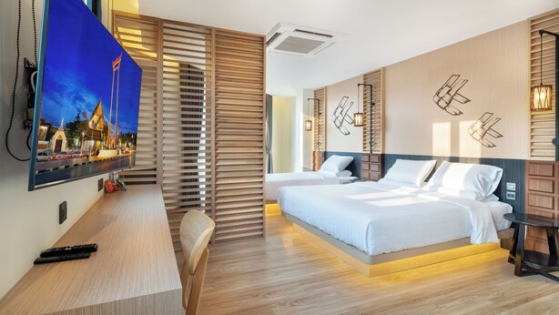 Una habitación de hotel moderna con una cama grande, un escritorio con televisor y paneles de madera.
