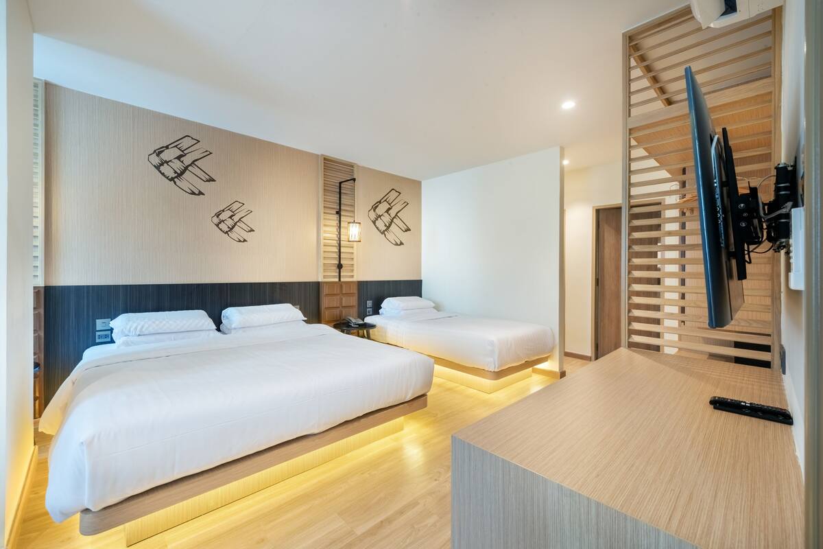 Une chambre d’hôtel moderne équipée de deux lits, d’une télévision et d’un bureau en bois.