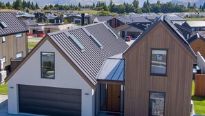 A modern residential area with houses featuring sloped roofs and a mix of wooden and metal exteriors. - Miharo Wanaka Retreat | Spa, BBQ & Mountain Views (Wānaka)